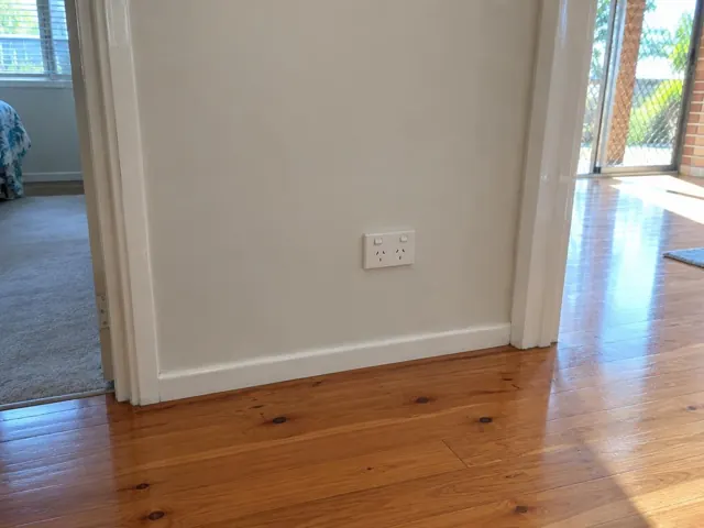 White double power point on a painted hallway wall beside doorways and timber floor in Palm Beach