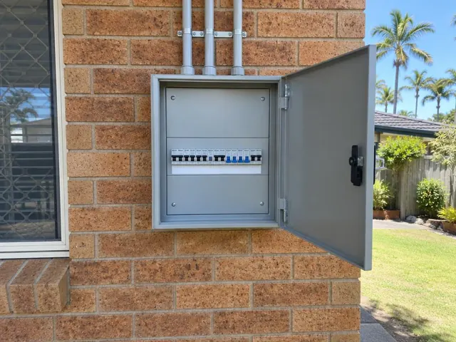 Open external switchboard on a brick house wall beside a window in Palm Beach